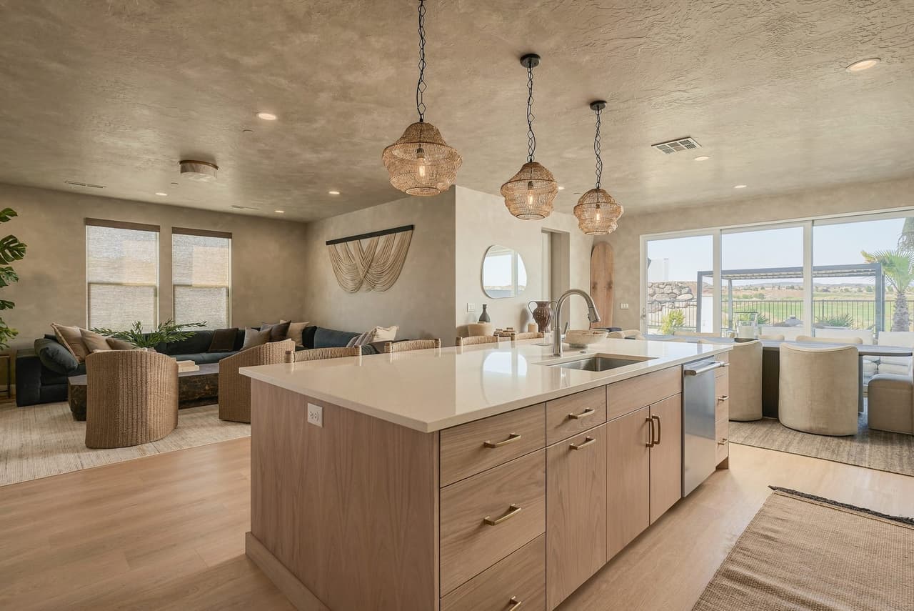 Open living, dining, and sage kitchen at Zephyr House looking out to the patio