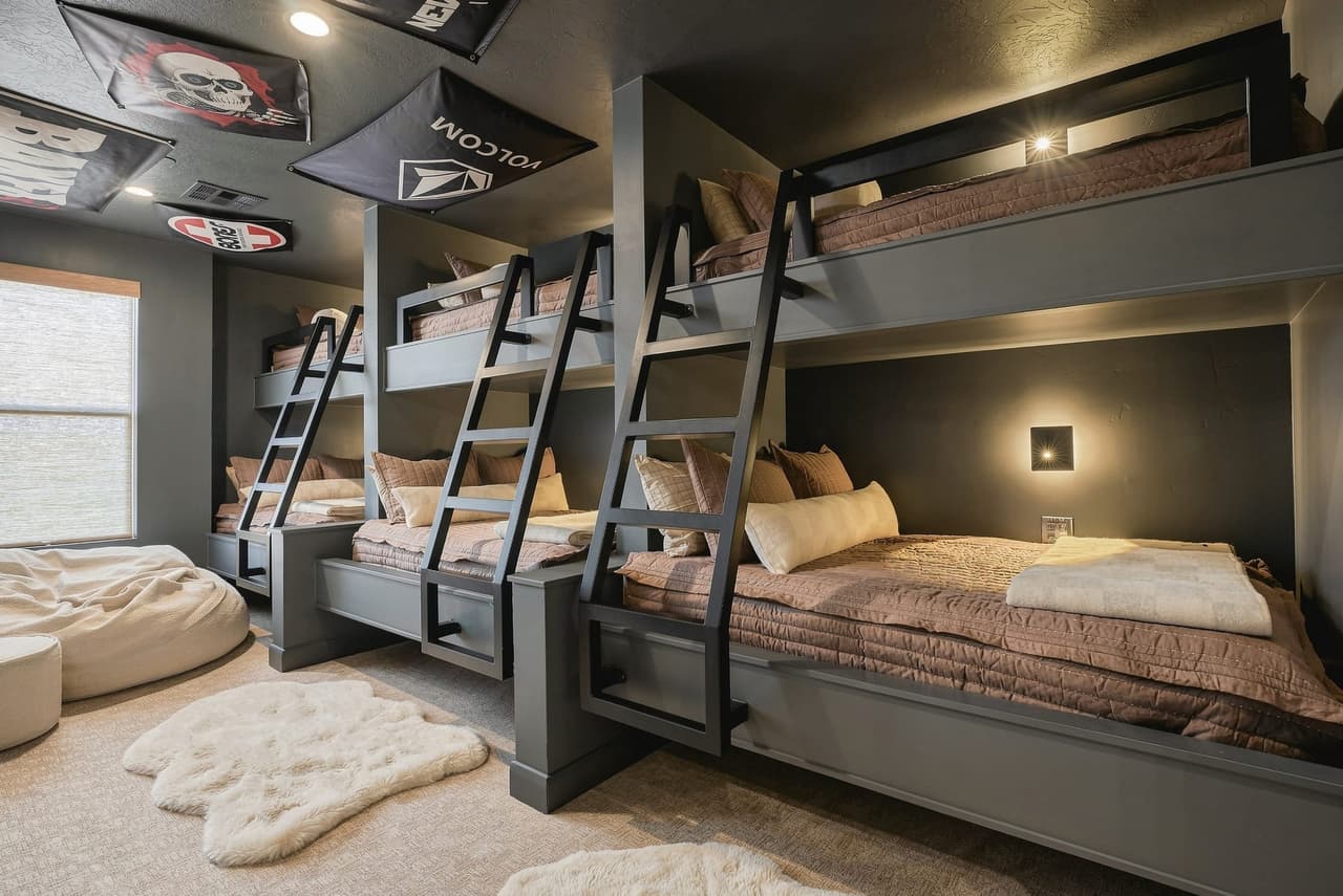 Snow bunk room at Zephyr House — six custom bunks with brown quilts and sheepskin rugs